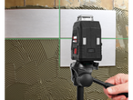 Una livella laser a croce ricaricabile PARKSIDE PERFORMANCE® con treppiede viene utilizzato per posare le piastrelle su un muro.