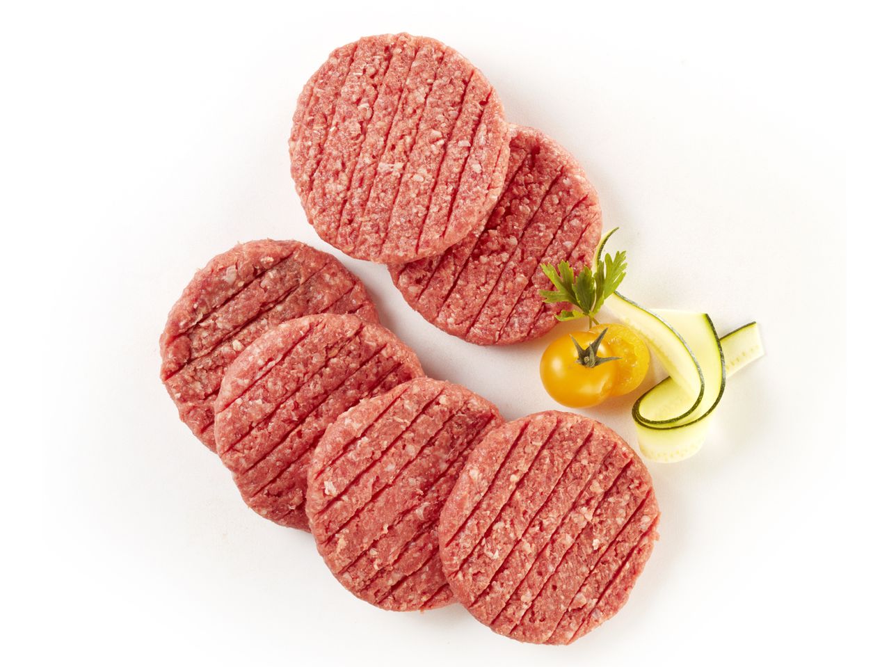 Hamburger di bovino crudi pronti per la cottura, con zucchine e pomodorini.