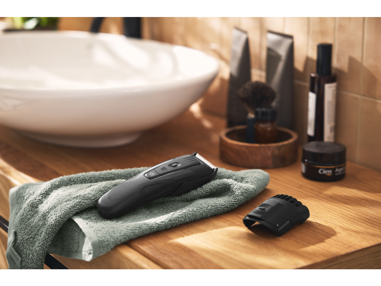 Aparador de cabelo e barba Cien sobre uma toalha, com cosméticos ao fundo.