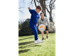 A father and son play with a football in a park.