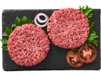 Kaks veiseliha kotletti mustal kivil alusel salatiga ja tomatitega.