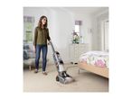 Woman cleaning a carpet with a Vax carpet cleaner in a bedroom.