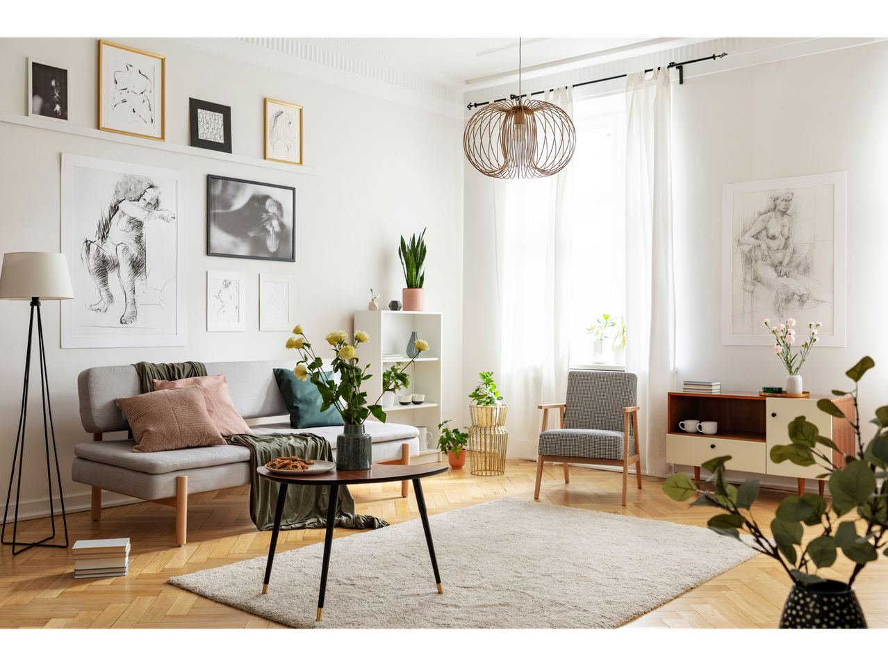 Sala de estar luminosa e moderna com sofá, poltrona, mesa de centro e quadros nas paredes.