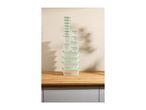 A tall stack of clear food storage containers with light green lids on a wooden countertop.