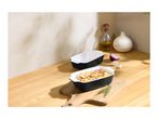 Two rectangular baking dishes, one filled with roasted potatoes, red onion, and herbs.