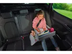 Bambina che gioca appoggiata su tavolo da viaggio mentre è in auto.
