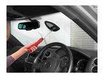 Person cleaning car windshield from inside with a long-handled cleaning tool
