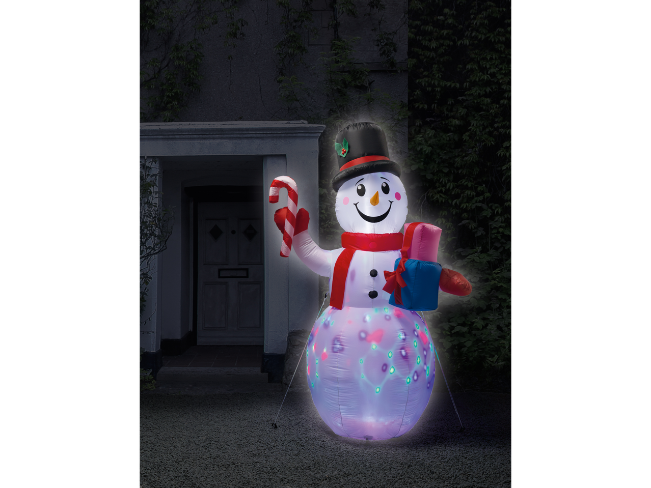 LIVARNO home Inflatable LED Christmas Figure, a snowman, in front of a house at night.