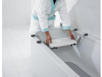Person placing a RIDDER® bath seat into a white bathtub.