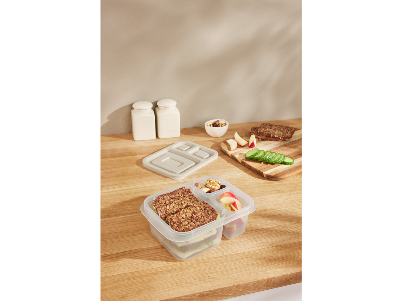 Transparent plastic bento box with sandwich and fruit.