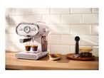 Pink SilverCrest espresso machine brewing coffee into two glasses on a wooden counter.
