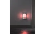 A red night light plugged into a wall socket, illuminating a dark room.