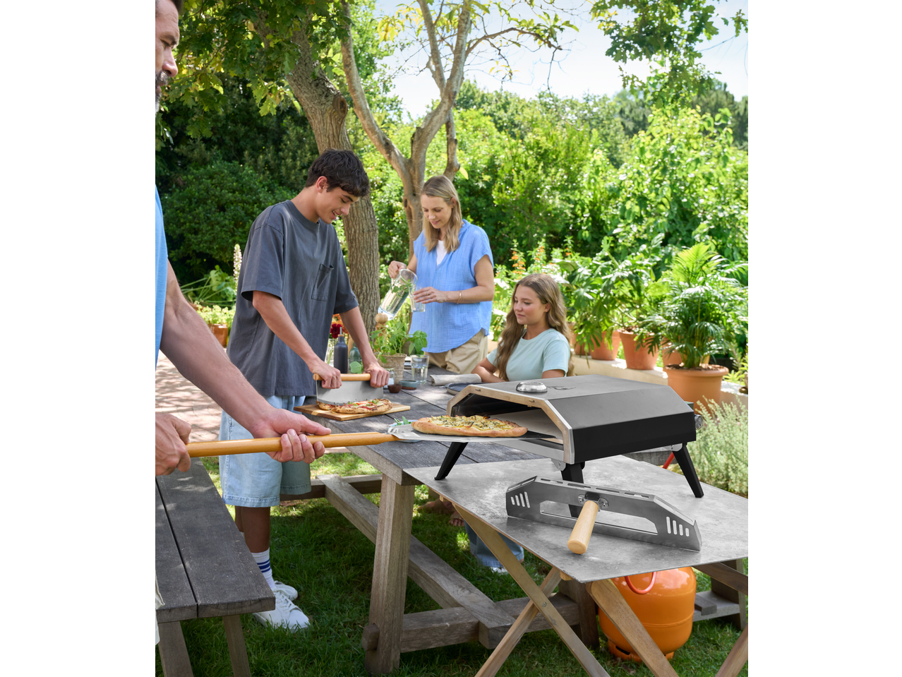 Cuptor de pizza de exterior cu o familie care face pizza într-o grădină însorită.