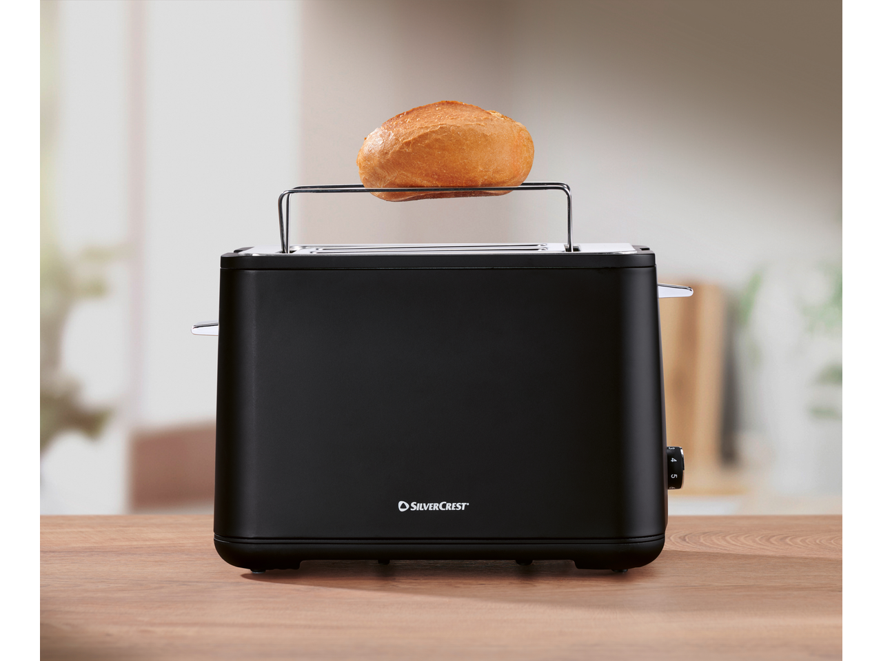 Black Silvercrest toaster with a bread roll on the warming rack.