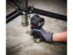 Una mano guantata usa un Avvitatore a percussione Parkside PERFORMANCE® per stringere una vite.