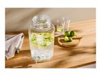 Glass drink dispenser with lime slices, two glasses, and limes on a wooden board.