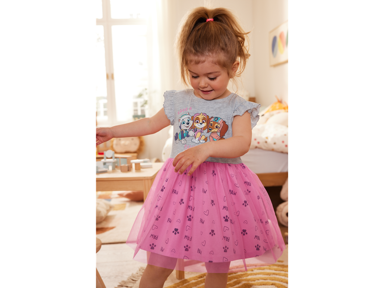 A toddler girl wears a pink Paw Patrol tulle dress.