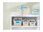 Beige plastic storage baskets with woven design hold cleaning supplies and laundry items on a white shelf.