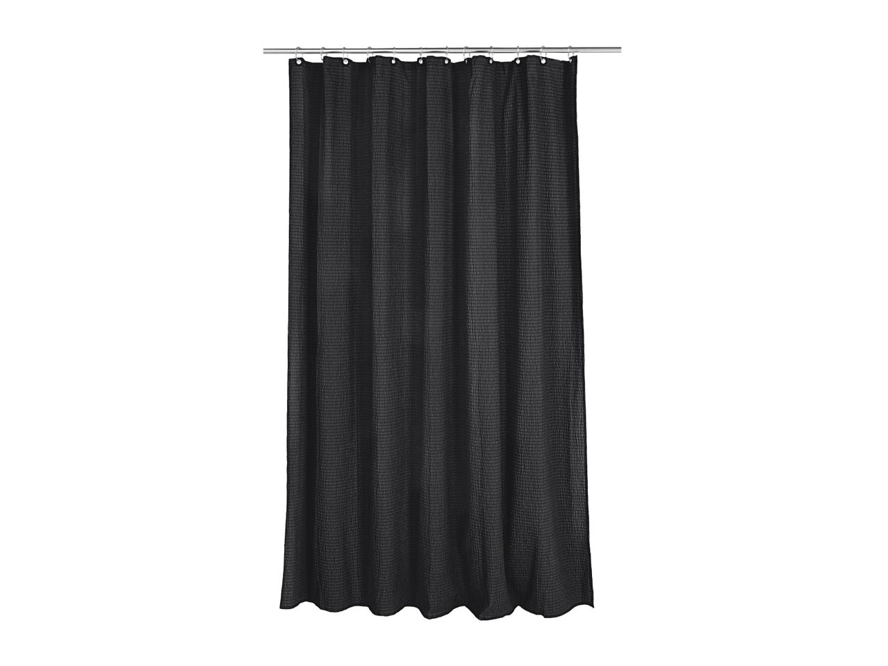 Black waffle weave shower curtain hanging from a silver rod with hooks.