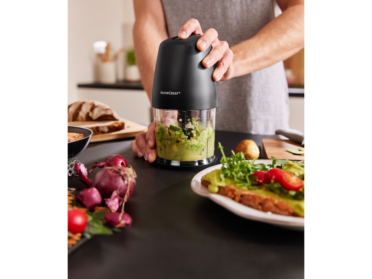 Un uomo prepara del guacamole con un tritatutto SilverCrest.
