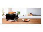 Black retro 4-slice toaster with '1973' text on a wooden kitchen counter next to a plate.