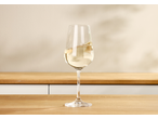 Copo de vinho com vinho branco sobre uma mesa de madeira, com fundo claro