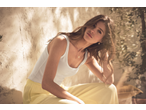 Woman in Esmara wide-leg trousers and white tank top, sitting in dappled sunlight.