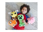 A smiling child lying on a rug, surrounded by four plush toys: a bee, a creeper, a fox, and a pig.