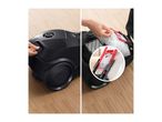 Vacuum cleaner with a hand opening the compartment to reveal the filter and dust bag.