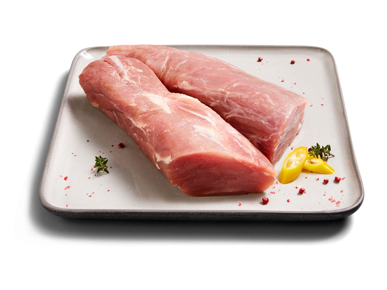 Zwei Schweinefilets auf einem Teller mit Pfeffer und Thymian.