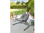Grey hanging egg chair with a side table and potted plants on a patio.