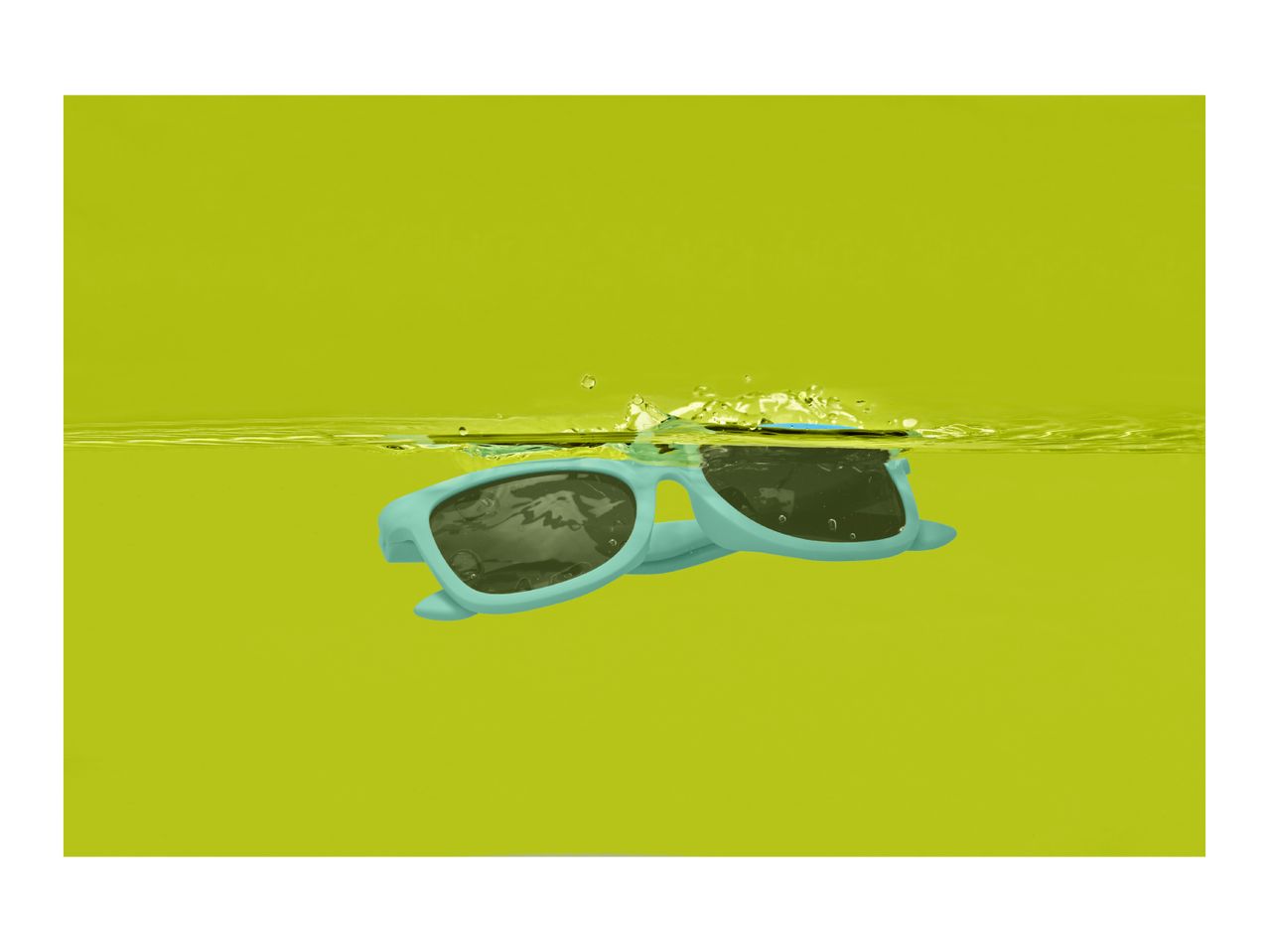 Blue sunglasses floating in yellow water with splashes.