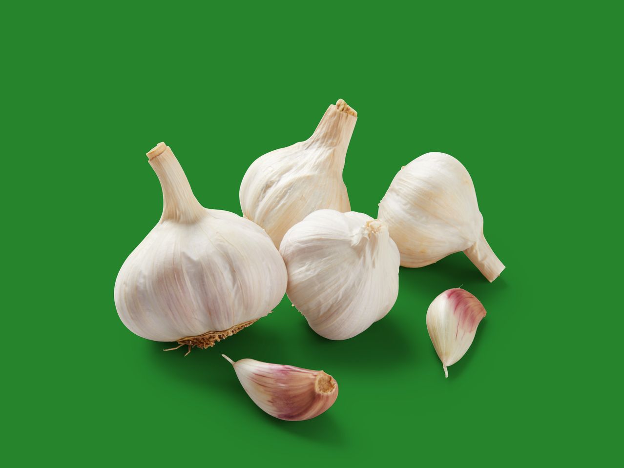 Frische Knoblauchzehen vor grünem Hintergrund.
