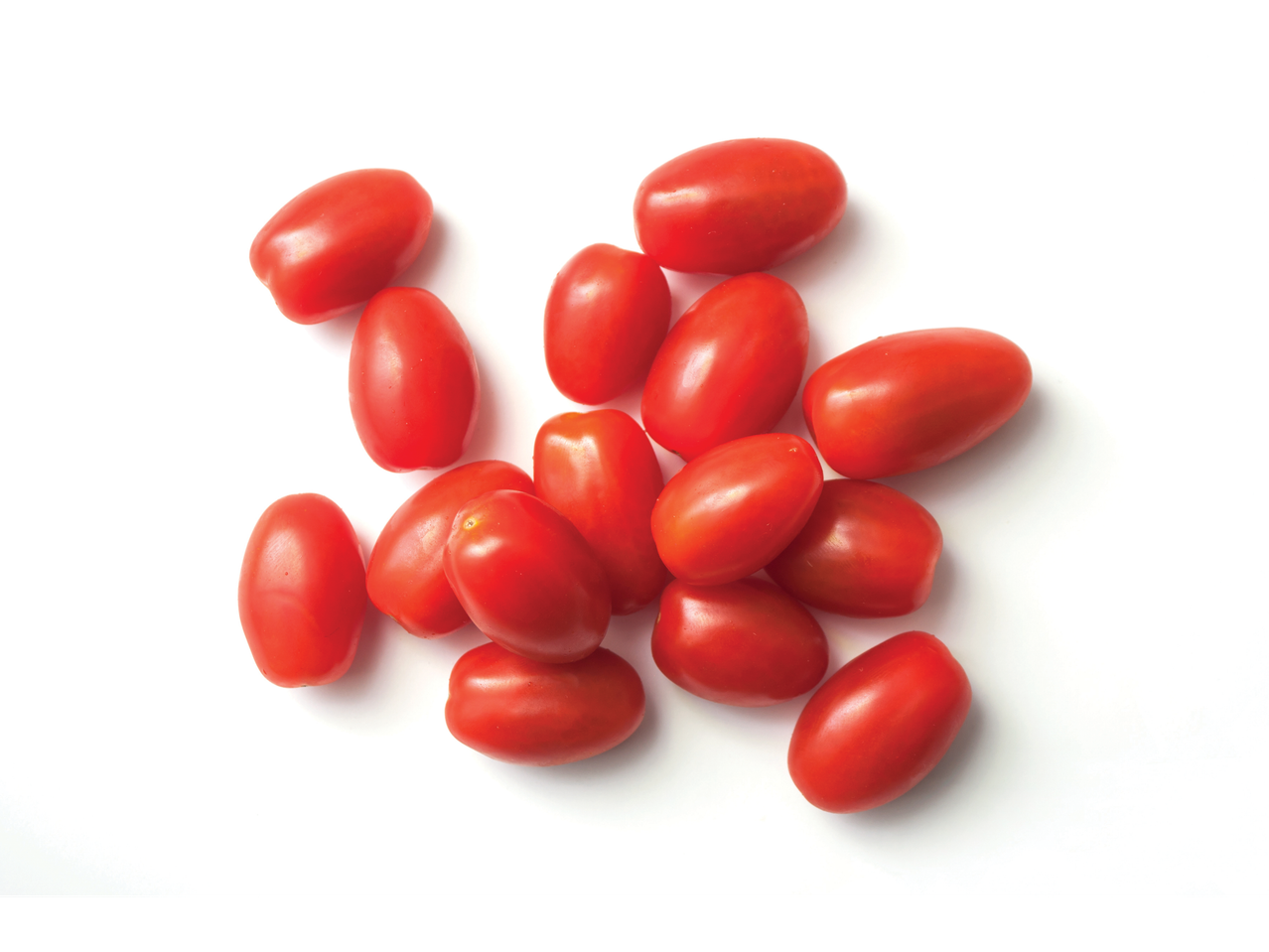 Tomates vermelhos maduros e frescos espalhados sobre fundo branco.