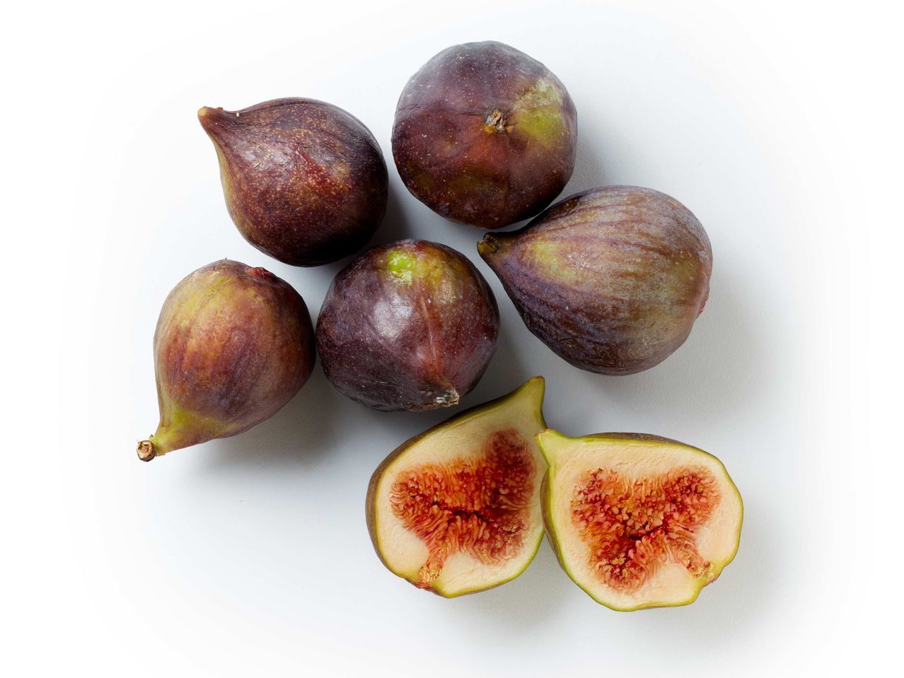 Fichi interi e tagliati a metà su sfondo bianco.
