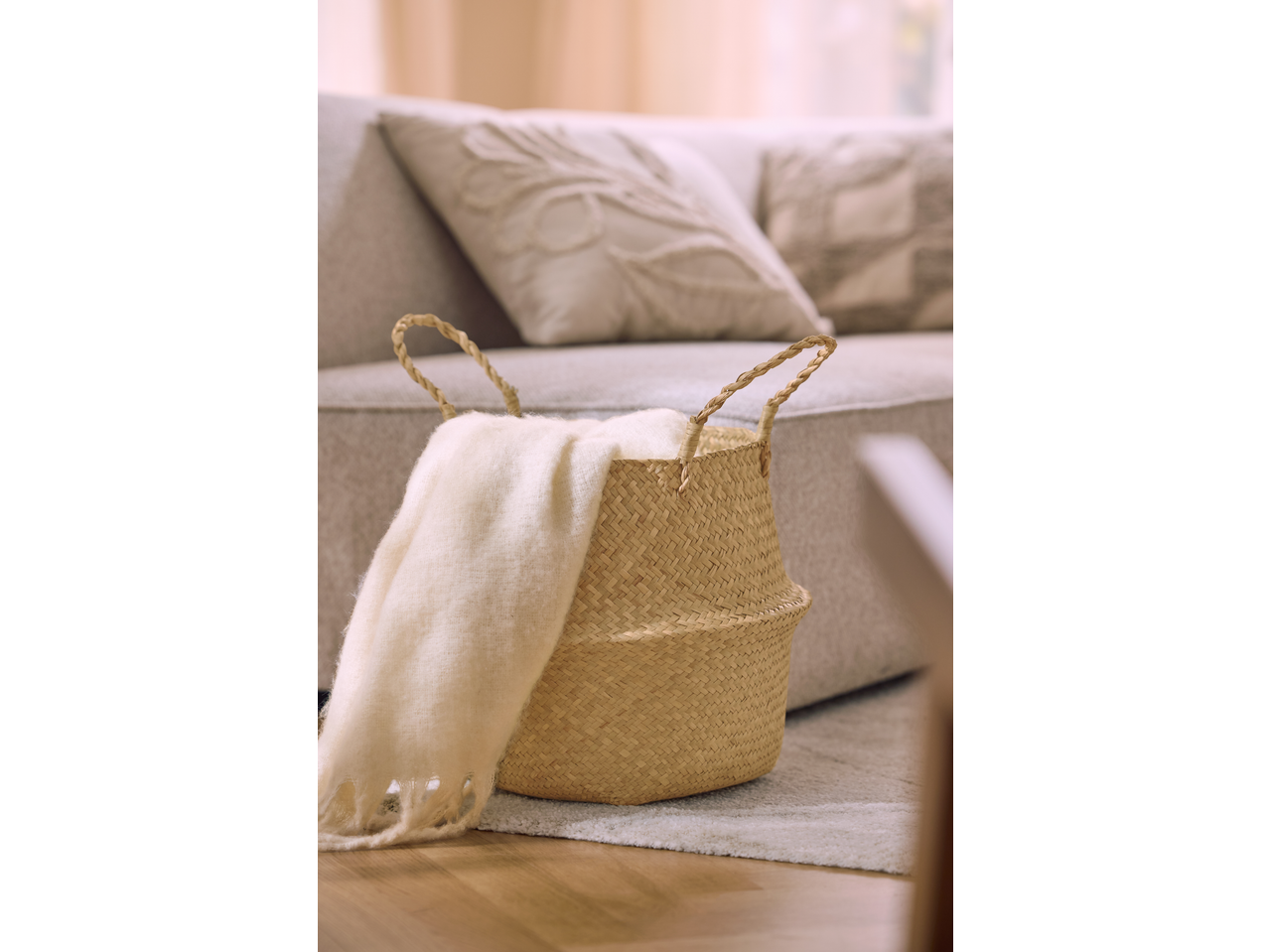 Διακοσμητικό καλάθι LIVARNO με κουβέρτα στο πάτωμα δίπλα σε καναπέ.