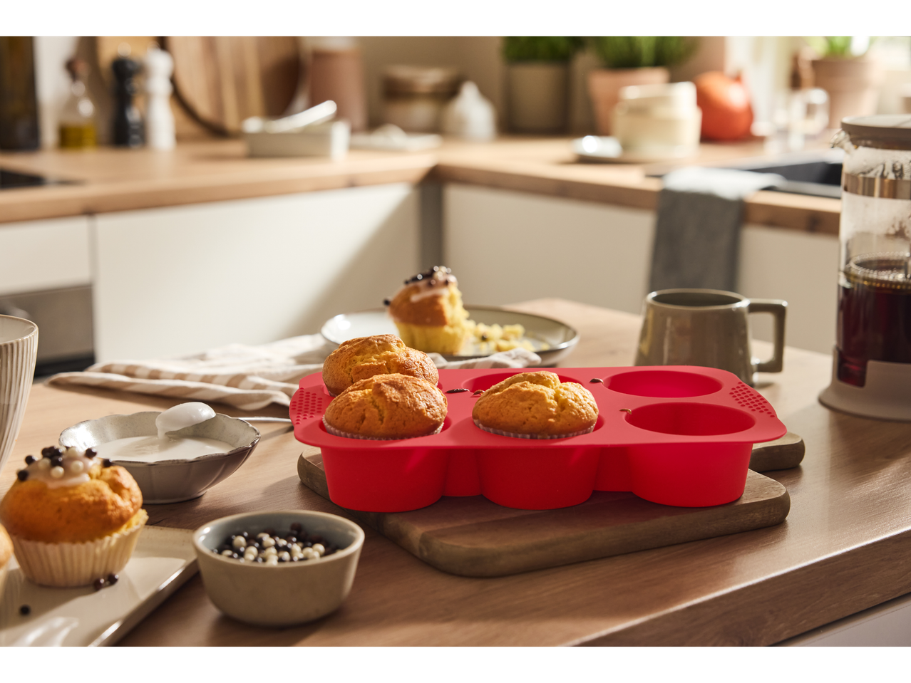 SILVERCREST® silicone muffin molds with baked muffins on a kitchen counter.