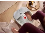 A person soaking their feet in a SENSIPLAST® foot bath with water on a wooden floor.