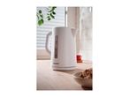 White electric kettle on a wooden kitchen counter with a bowl of cookies.