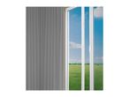 Grey pleated blinds next to a white framed door with a view of a green field and blue sky.