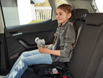 Ein Kind sitzt in einem Autokindersitz auf dem Rücksitz eines Autos.