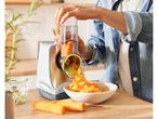 A person uses a SILVERCREST® KITCHEN TOOLS Electric grater to shred carrots into a bowl.