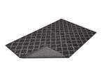 Dark grey patterned rug with a white geometric design, partially folded to show the underside.