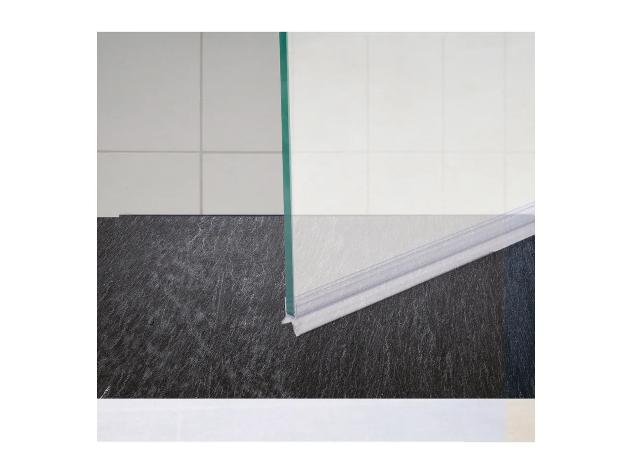 Shower door with a clear bottom seal and a dark textured floor.