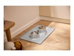 Two pet bowls with food and water on a grey silicone mat on a wooden floor