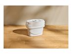 White water filter cartridge on a wooden surface with natural light and shadows.