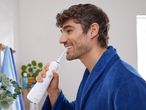 Man using a Nevadent oral irrigator in his bathroom.