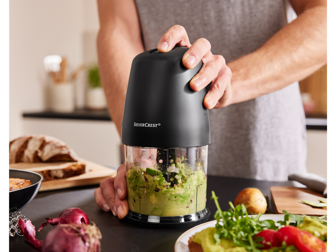 A person uses a SilverCrest mini chopper to make guacamole.