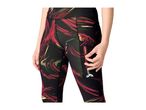 Woman wearing black leggings with red and green abstract patterns, opening a side zipper pocket.