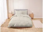 Un letto con testiera grigia e lenzuola color crema, affiancato da comodini in legno.